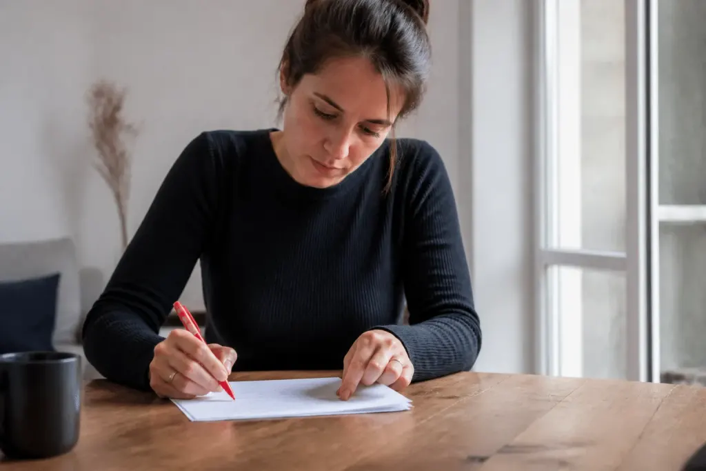 Locataire relisant document bail avec stylo rouge sur table